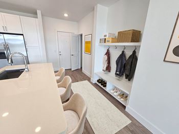 A white kitchen with a sink and a row of chairs.